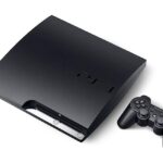 PlayStation 3 console beside a PC displaying the RPCS3 emulator interface.